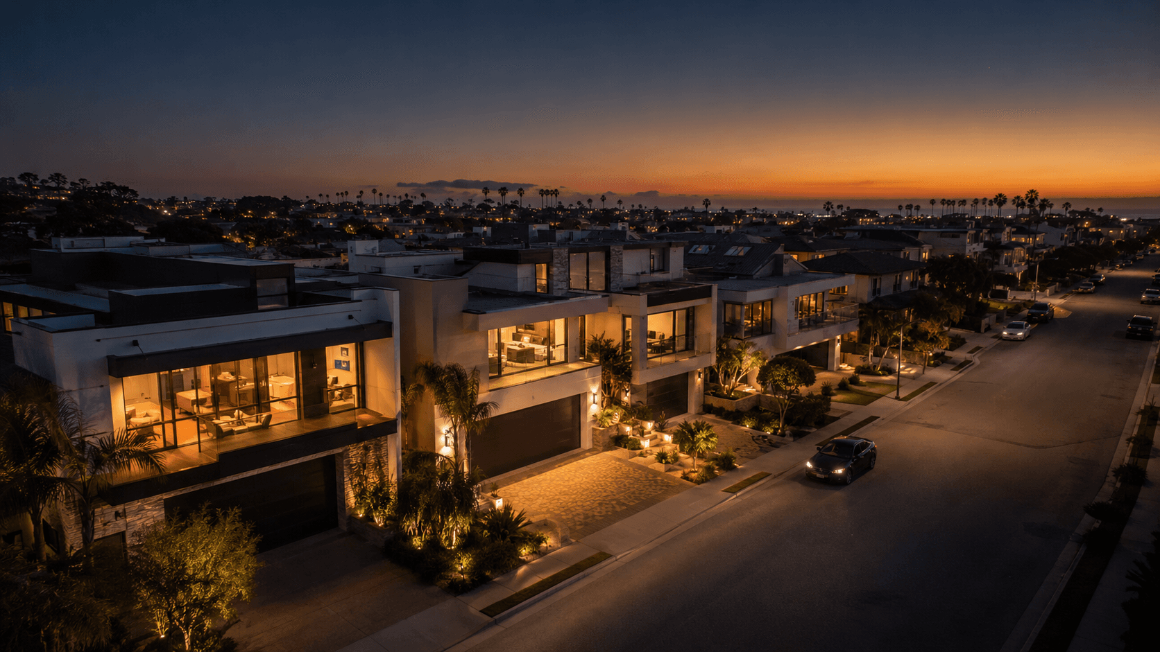 Aerial view of modern luxury homes along a coastal street at twilight